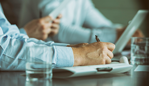 man holding pen and writing in a meeting